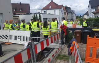 ExkursionsteilnehmerInnen stehen an der Baugrube des Wärmenetz in Tamm und betrachten Nahwärmerohre.